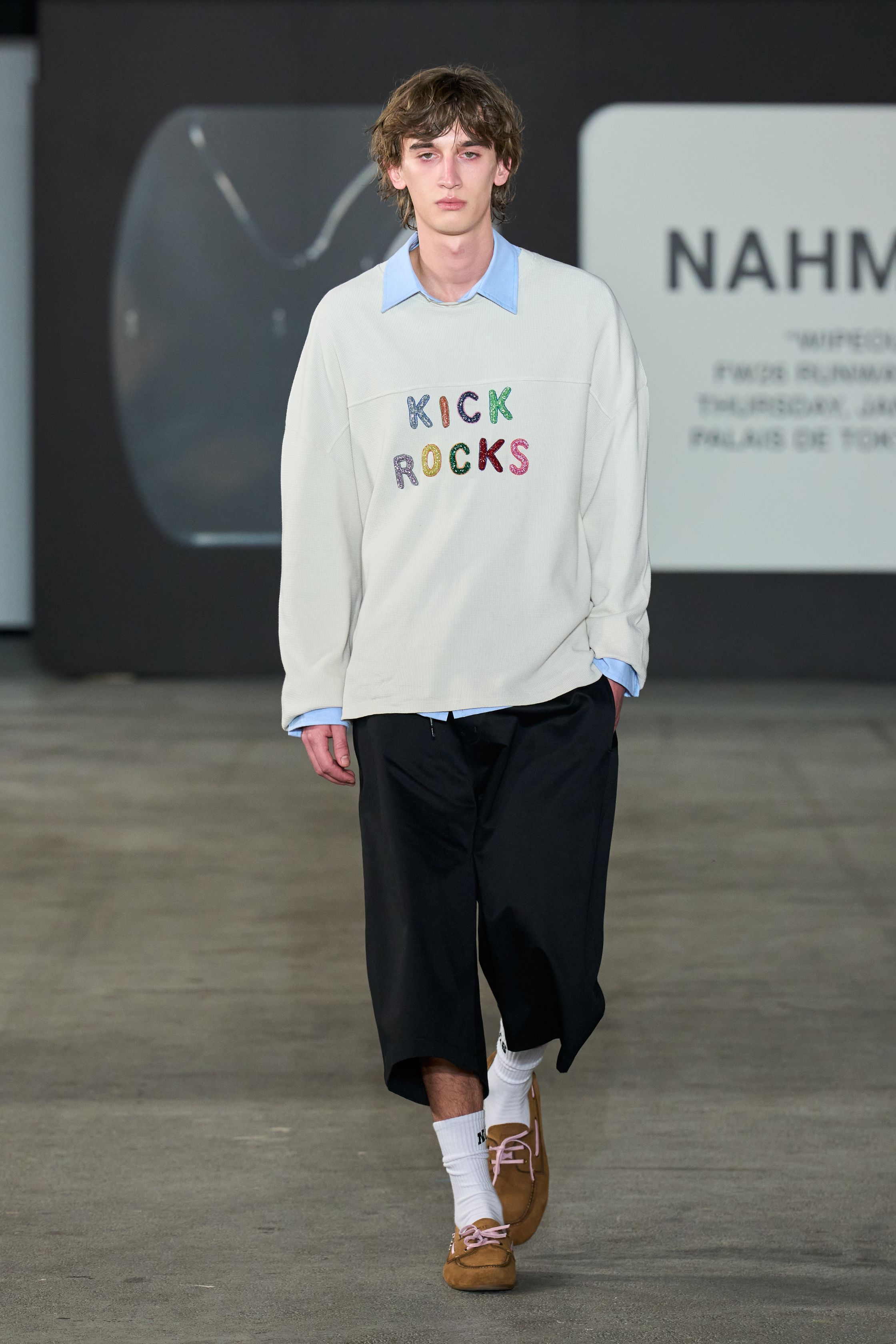 Nahmias 2026秋冬将洛杉矶滑板文化与怀旧流行符号并置，打造一场带有讽刺意味的青春景观。宽松裤装、学院感上衣与玩味图案形成轻松而不设防的氛围，滑板与面具式造型强化表演性。系列并不追求精致，而是通过“不完美”的搭配捕捉西海岸随性、反精英的生活态度，呈现一种带着玩笑感的现实主义-顽石频道趋势研究